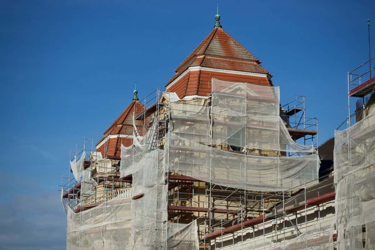 Eingerüstete Altbaufassade mit Schutznetz vor blauem Himmel — Beispielfoto