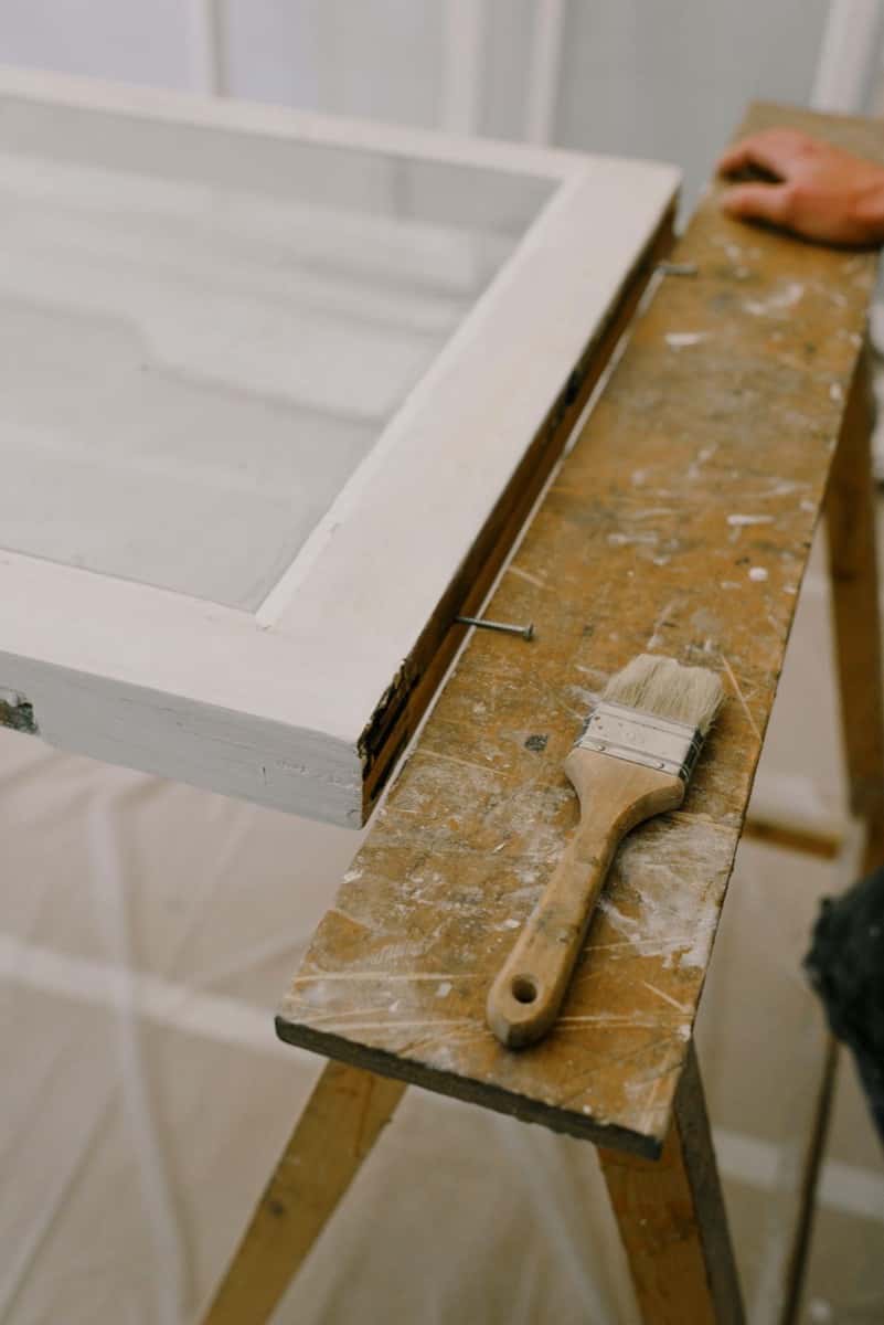 Weiß lackiertes Fensterelement auf Arbeitsböcken mit Flachpinsel — Beispielfoto